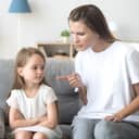 young mother scolding her little daughter in their living room