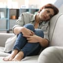 Depressed young woman sitting on sofa
