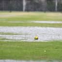 A green softball sits on a waterlogged field as it's raining.