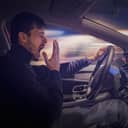 A person yawning while driving a car
