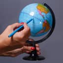 Close-up of the globe and a blue pencil aligned along the equator.