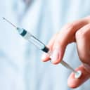 close-up of a hand holding a medical syringe with a needle, ready for vaccination or injection