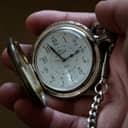 close-up of an open silver and gold pocket watch in a person's hand