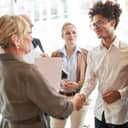 A businesswoman, in her role as a boss, congratulating a young man on a promotion or success.