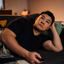 Adult man lying on sofa and watching tv in cozy living room at home.
