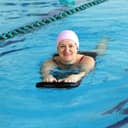 a middle aged woman learning how to swim in a swimming pool