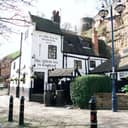 An inn with a white facade that has 'the oldest inn in England' written on it near a fortress