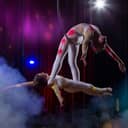 Circus acrobats perform on a dark stage.