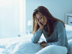 A tired woman sitting up in a bed