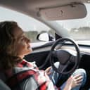 A woman driving a Tesla in an autonomous mode without controlling the vehicle