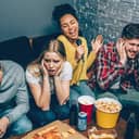 A girl singing during karaoke night with her group of friends, leading them to cover their ears.