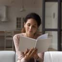 A woman sitting on a couch, reading a book