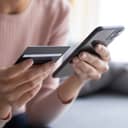 Close-up of a woman's hands as she uses a credit card and smartphone to make an online payment.