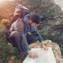 Lost hiker with backpack checks map to find directions in wilderness area