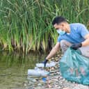 Close Up of Person Collecting Plastic From the River. Man Cleaning River of Plastics. Environment Concept.
