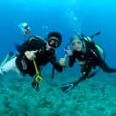 two scuba divers equipped with a compact underwater camera and flashlight in the clear blue waters of Koh Chang, 2009.