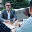 smiling businesspeople having a cheerful team meeting at a rooftop table