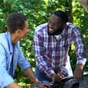 Black father explaining car structure to son and smiling, teamwork, family