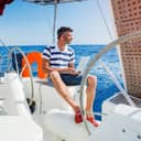 Portrait of a young man working on his laptop aboard a sailboat.