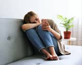 Young woman sitting on a couch and looking at her phone