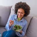 Woman on sofa eating a fruit salad