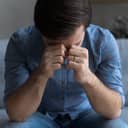 close-up of a distressed young man experiencing an emotional turmoil while sitting on a couch