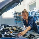 Female mechanic working under the hood of a car