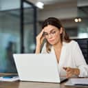 businesswoman with glasses feeling stressed and fatigued, annoyed with her laptop not working properly