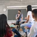 Teenager students listening and talking to friendly young male teacher - Group discussion in High School Education