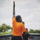 He shoots and scores. a referee blowing his whistle while lifting his hand up in the middle of a rugby match on a field during the day.
