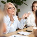 experienced businesswoman with glasses speaking to her team during the meeting in an office