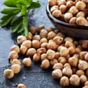 Fresh chickpeas scattered on the table next to a bowlful of more chickpeas