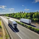 Two cargo trucks driving on the high way in opposite directions.