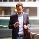 A man in a suit walking and looking at his phone
