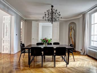 Big dining room with hard-wood floor, in an older European building.