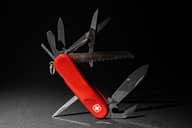 Swiss army knife on a metallic surface against dark background