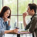 Close-up of a young couple enjoying a date at a coffee shop, with a coffee cup, laptop and books on the table.