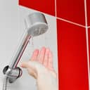 Close-up of the shower head, experiencing low water pressure with just a few droplets coming out.