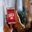 A woman holding a phone with a "Christmas Sale" ad