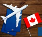 Model airplane, two passports, and small flag of Canada on table