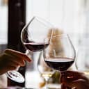 close-up of a young couple's hands toasting with glasses of red wine at a restaurant