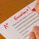 Teacher grading a paper with "A+ Excellent!"