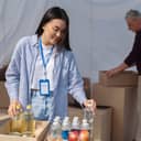 two volunteers sorting food in cardboard boxes in a shelter
