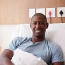A smiling man sitting in bed in a hospital