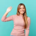 young pretty woman smiling happily, waving hand, welcoming and greeting the camera
