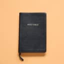 Close-up of the Holy Bible on a vibrant orange background.