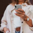 woman in white coat holding silver iphone 6