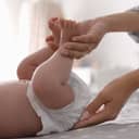 close-up of a mother attentively changing her baby's diaper on a bed