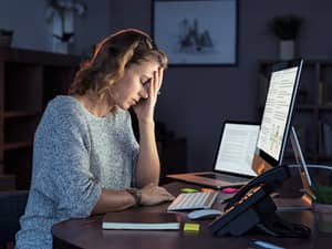 A tired young woman sitting in front of a computer at night