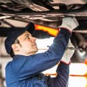 A mechanic checking the underside of a car